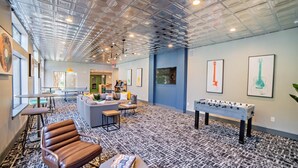 A spacious lounge area with a foosball table, comfortable seating, and artwork on the walls. - Homey Modern 3BR Retreat w/Resort Pool (Austin)