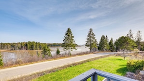 A view from a balcony overlooking a road, a body of water, and a forested area. - Bay Views: Peaceful Acadia National Park Getaway! (Steuben)