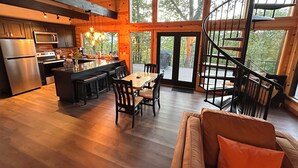 Une cuisine spacieuse dotée d’un îlot central, de planchers en bois et de grandes fenêtres offrant une vue sur l’extérieur.