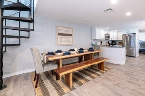 A modern kitchen with white cabinets, a stainless steel refrigerator, and a dining area with a wooden table and bench. - Steps to Beach: Lake-View Laconia Getaway! (Laconia)