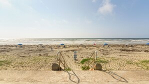 A sandy beach with umbrellas and a lifeguard stand.