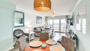 A spacious living area with a dining table, sofas, and a ceiling fan.