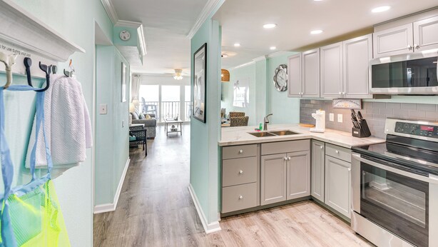 A modern kitchen with grey cabinets, a stainless steel oven, and a microwave.