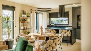 A modern kitchen with a central island, built-in appliances, and a dining area with a round table and unique chairs.