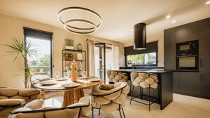 A modern kitchen with a central island, built-in oven, and a pendant light.