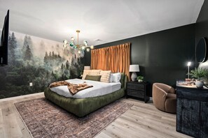 A bedroom with a bed, a nightstand, a chair, a dresser, and a forest mural on the wall.