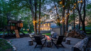 A backyard with a fire pit, outdoor seating, a play structure, and string lights. - Dream House | HotTub+Game Room | 11mi to Camelback (Pocono Summit)