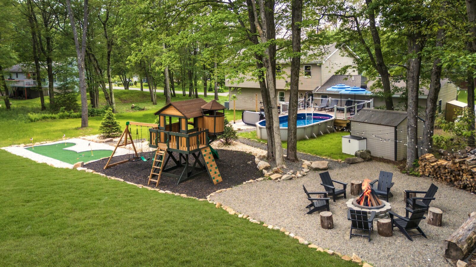 A backyard with a wooden playhouse, a small pool, and outdoor seating.
