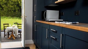 Een keuken met donkerblauwe kastjes, een magnetron en een houten aanrecht.