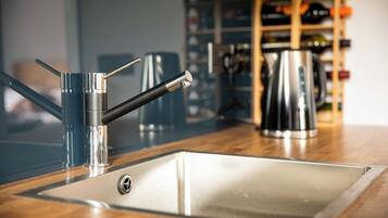 A kitchen with a stainless steel sink, a modern faucet, and a kettle on the counter.