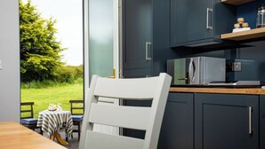 A modern kitchen with dark cabinets, a microwave, and a coffee maker on the countertop. - Donegal Manor (Donegal)