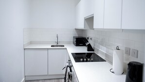 Una cocina moderna con armarios blancos, una estufa negra y un microondas.