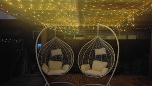 Two white hanging chairs with cushions and a wooden deck. - Beautiful Studio w/Parking | Near CBD & Port Hills (Christchurch)