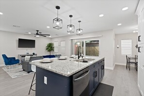 A modern kitchen with granite countertops, stainless steel appliances, and pendant lighting.