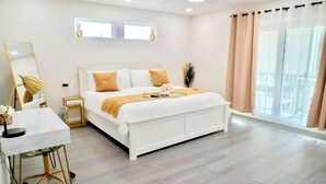 Un dormitorio moderno con una cama grande, una mesita de noche, un escritorio y una ventana con cortinas.