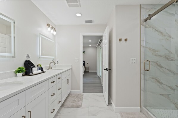 A modern bathroom with a large mirror, a sink with a towel rack, and a shower area.