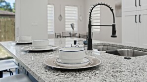 Una cocina con encimeras de granito, armarios blancos y un fregadero de acero inoxidable.