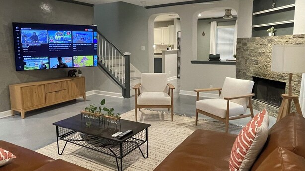 A modern living room with a flat-screen TV, a staircase, a fireplace, and a leather couch. - Centrally Located 4-Bed Getaway with 2.5 Baths (San Antonio)