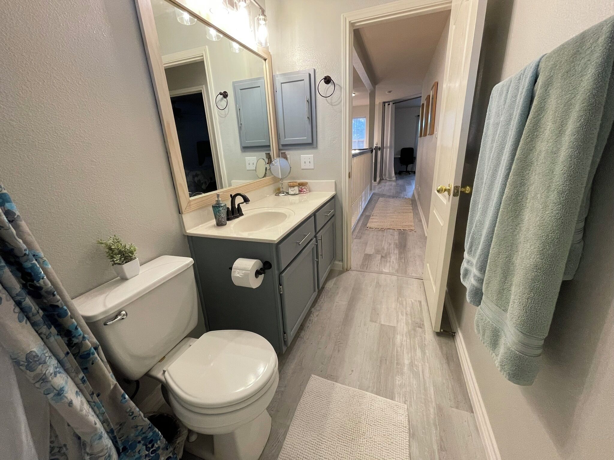 A bathroom with a toilet, sink, mirror, and towel rack.