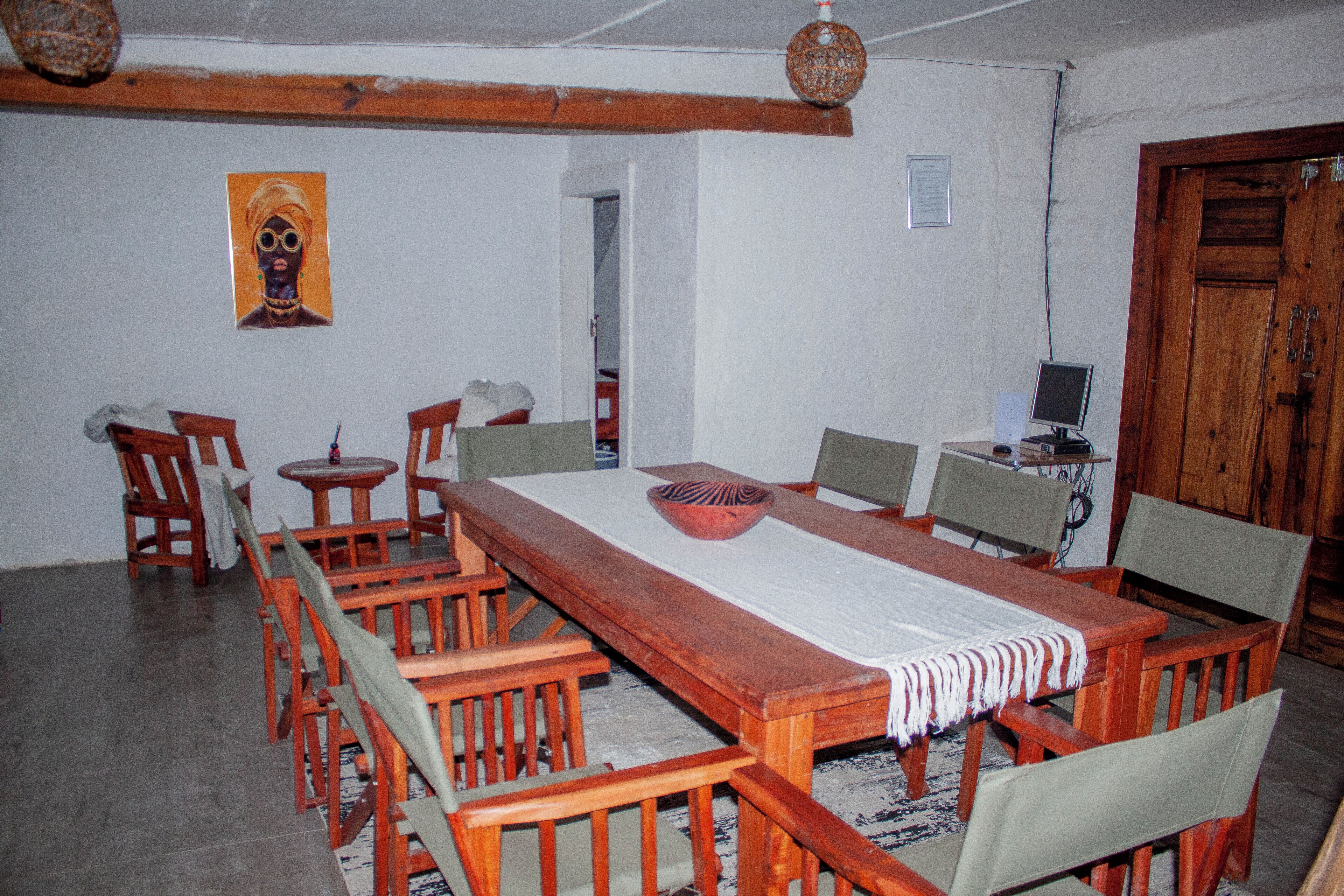 A dining area with a long wooden table, multiple chairs, a small side table, and a decorative bowl.
