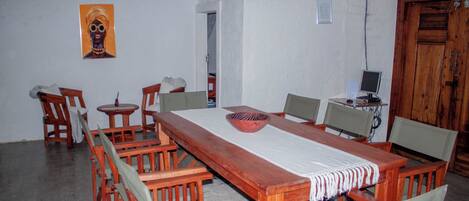 A dining area with a long wooden table, multiple chairs, a small side table, and a decorative bowl.