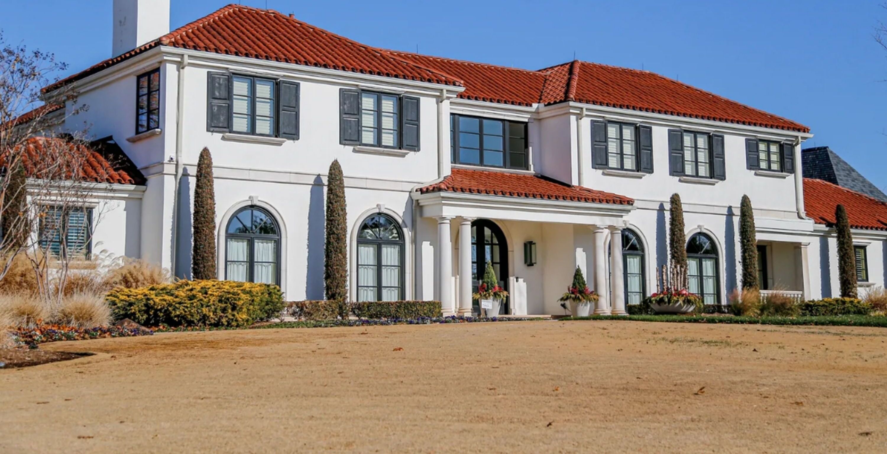 A large, two-story house with a red-tiled roof, multiple windows, and a well-maintained garden.