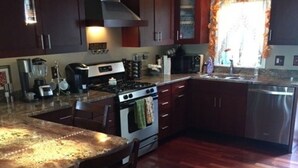 A kitchen with a central island, wooden cabinets, a stove, and a dishwasher.
