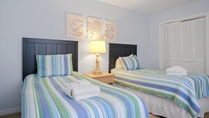 A hotel room with two beds, each with striped bedding, a bedside lamp, and artwork on the wall. - Fairway Haven – Minutes to Beach & Harbour Town (Hilton Head Island)