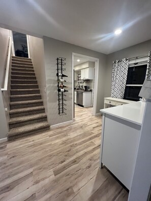 A modern kitchen with white cabinets, a wooden floor, and a built-in wine rack. - Charming 3-bedroom house in pleasant Monroe with WiFi, and A/C (Monroe)