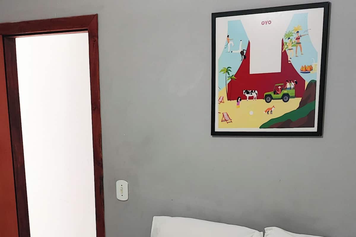 Ένα υπνοδωμάτιο με ένα κρεβάτι, λευκά μαξιλάρια και μια κορνιζαρισμένη εικόνα στον τοίχο.