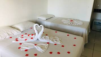 Two beds with white linens, red rose petals, and swan-shaped towels.