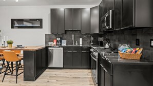 Una cocina moderna con armarios oscuros, una isla central, electrodomésticos de acero inoxidable y un salpicadero.
