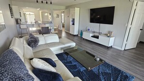Ein modernes Wohnzimmer mit einem Ecksofa, einem Couchtisch und einem Flachbildfernseher.