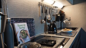 A modern kitchen with stainless steel appliances, a kettle, and a bowl of food on the counter.