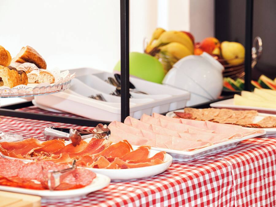 Una mesa de buffet con diversos alimentos, como pasteles, carnes y frutas.
