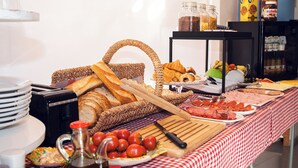 Una mesa de buffet con diversos alimentos, incluyendo pan, tomates y una tabla de cortar con un cuchillo.