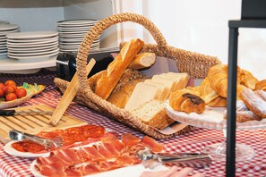 Un buffet de petit-déjeuner comprenant du pain, des viennoiseries et de la charcuterie.