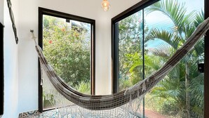 A hammock in a room with large windows, patterned floor tiles, and a hanging light fixture. - Casa com piscina Praia da Vila Nova (Imbituba)