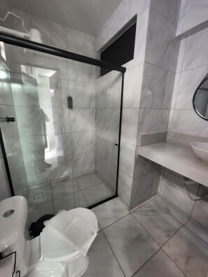 A modern bathroom with a glass-enclosed shower, a white toilet, and a marble-tiled floor. - Malai Pousada (Joao Pessoa)