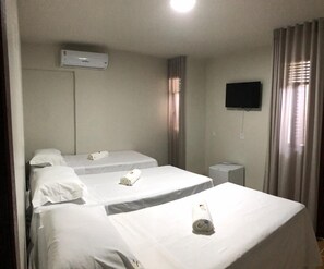 A hotel room with three beds, a TV mounted on the wall, and an air conditioning unit. - Malai Pousada (Joao Pessoa)