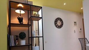 Una sala de estar moderna con una estantería, una lámpara, un reloj y un sillón.