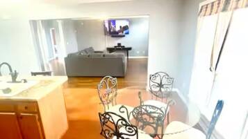 Un amplio espacio habitable con cocina, comedor y televisor montado en la pared.