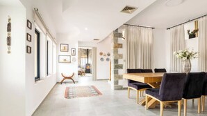 Un comedor moderno con una mesa y sillas de madera, una pared decorativa de piedra y vistas a otra habitación.