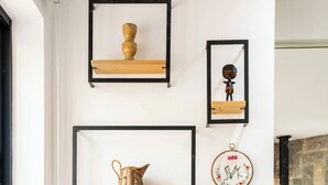 Un rincón de una habitación con un banco de madera, una chimenea y estantes en la pared con objetos decorativos.