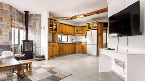 Una cocina moderna con armarios de madera, estufa empotrada y televisor de pantalla plana.