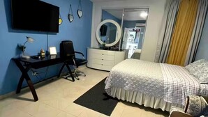 A bedroom with a bed, a desk, a chair, a TV, a dresser, and a mirror. - The Retreat - 5 min to Airport (Carolina)