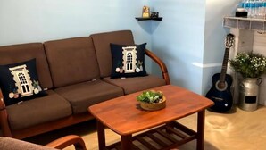 A cozy living room with a brown sofa, a wooden coffee table, and a guitar. - The Retreat - 5 min to Airport (Carolina)