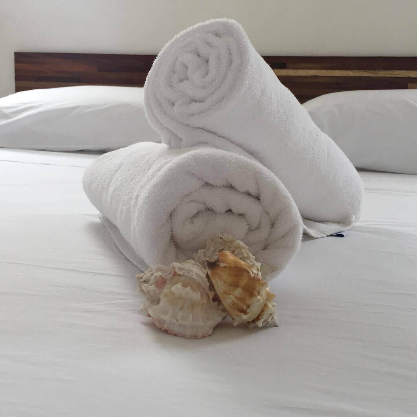 Un lit bien fait, avec du linge de lit blanc et des serviettes blanches roulées.