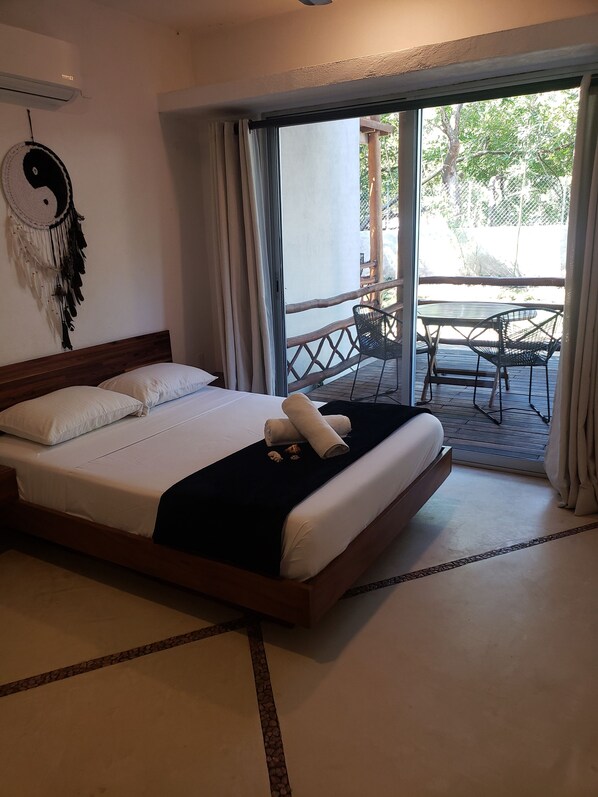 Camera d'hotel con un letto, un acchiappasogni e vista su un patio esterno con tavolo e sedie.
