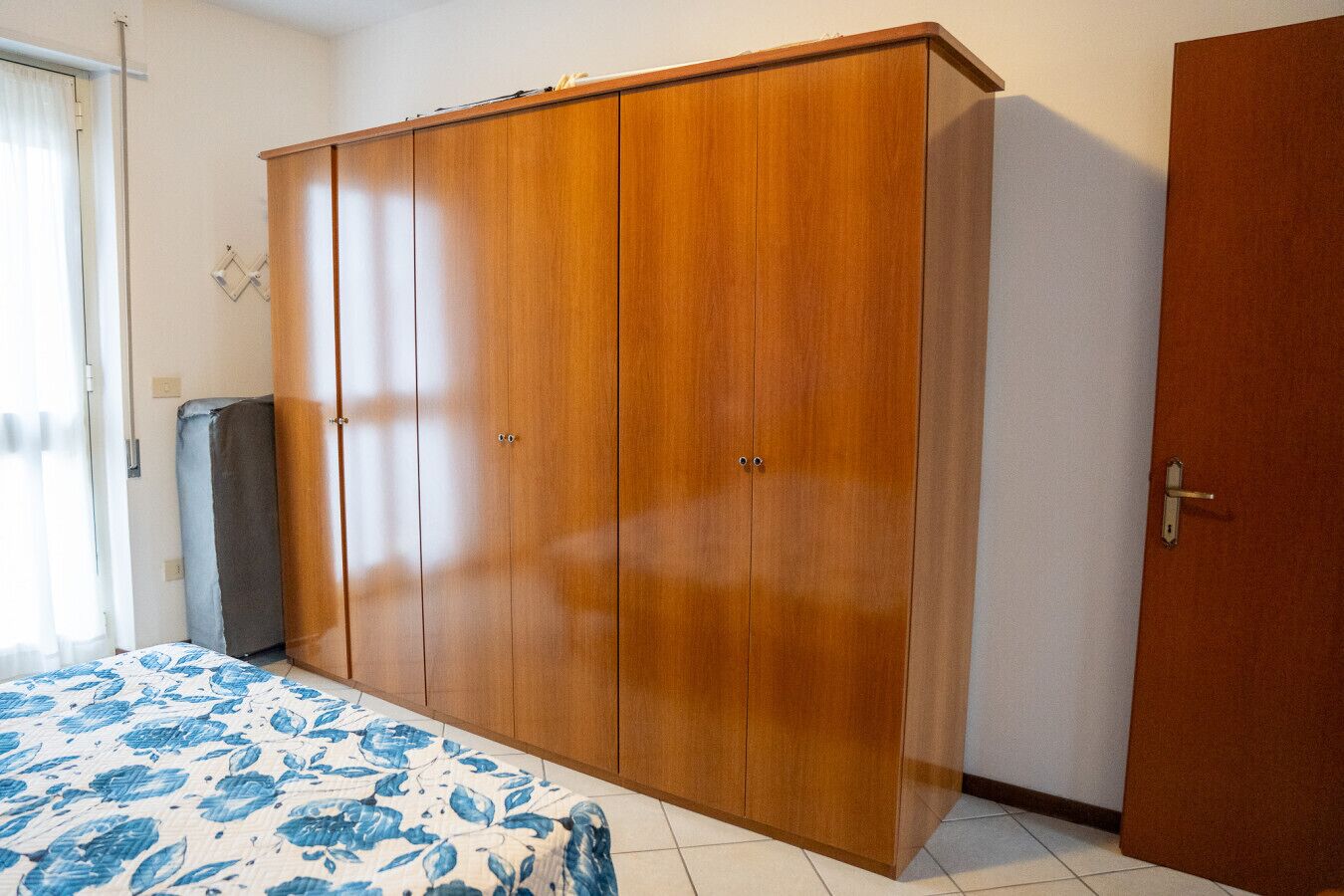 A bedroom with a bed, a wardrobe, and a door.